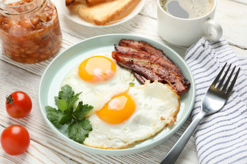 Delicious breakfast or lunch with fried eggs on wooden background, close up