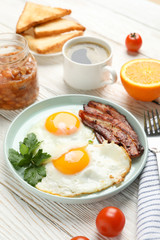 Delicious breakfast or lunch with fried eggs on wooden background, close up