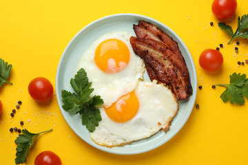 Delicious breakfast or lunch with fried eggs on yellow background, top view