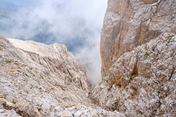 Fototapeta na wymiar Low clouds and fog on a mountain couloir, at via ferrata Eterna Brigata Cadore route on Marmolada glacier, Dolomites mountains, Italy.