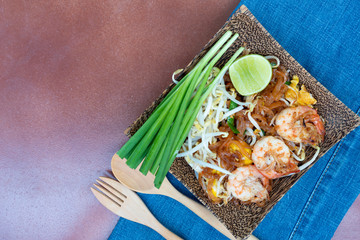 Pad Thai with Fresh Shrimp or Fried noodle Thai style with prawns. On a plate from natural materials produced by coconut trees. Place on the tile floor. With a handle to lift off the floor.