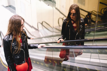 Thoughtful young woman standing on escalator in shopping mall
