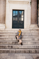  portrait of young European Muslim women with hijab exploring old city of Split as tourist. Diocletian's palace. She is sitting on stairs. 