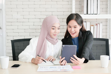 Two beautiful ladies talking about the new business project together in their office . Two business woman take a break in the evening.