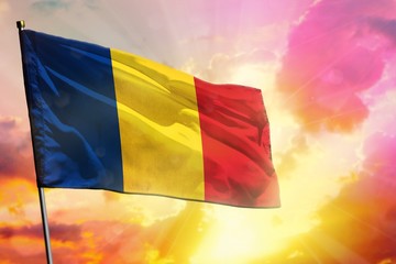 Fluttering Romania flag on beautiful colorful sunset or sunrise background. Success concept.
