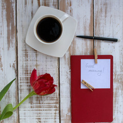 Good morning wishes on an office desktop with a cup of coffee and a beautiful tulip flower. Gift to a colleague to a woman.