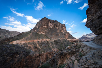 View of the dirt road between mountains on a cloudy day in Jebel Shams, Oman
