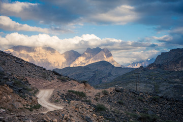 View of the dirt road between mountains on a cloudy day in Jebel Shams, Oman