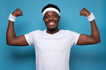 Happy strong man in sport gym, shows muscles, glad to be fit and healthy. Sportsman enjoys workout,...