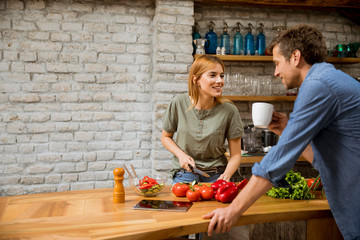 Young  woman cooking while man drinking coffee