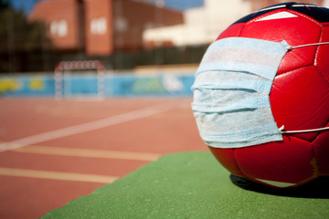 coronavirus soccer concept, ball with mask on soccer field, school