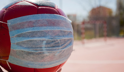 coronavirus soccer concept, ball with mask on soccer field, school