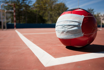 coronavirus soccer concept, ball with mask on soccer field, school