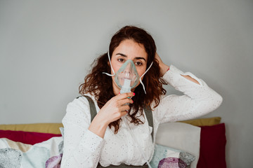 Young woman with weak health using assisted breathing at home. Treatment of a respiratory disease...