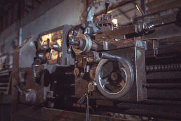 Fototapeta na wymiar closeup of Old metallic lathe working against factory industrial interior background.
