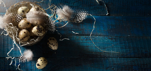 Easter banner background; Retro style picture with Easter eggs and feathers in silver basket  on dark blue background. Top view, flat lay with copy space.