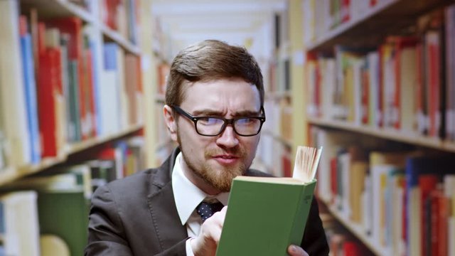 Real portrait of handsome smart man entrepreneur reading a story book speaking quote words surprised smiling happy posing in the library.