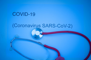 Coronavirus text written and stethoscope isolated on blue dramatic background