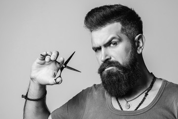 Business, barber shop. Brutal handsome hairstylist. Barber holding scissors. Male bearded style,...