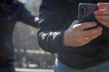 man in black coat hold smartphone and take photo