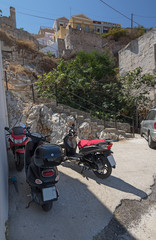 Street transport on the island of Symi, Greece. Old bicycle, moped and motorcycle on the background of the old cobblestone stairs.
