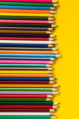 Colorful multicolor pencils on yellow background. flat lay top view copy space vertical layout
