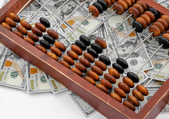 Old wooden abacus on a paper american dollars background.