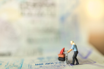 Travel Concept. Male traveler miniature figure people with baggage on airport trolley walking on...
