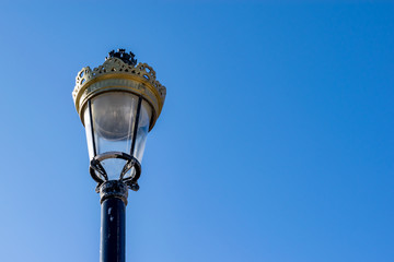 Fototapeta na wymiar Vintage lampost featuring a beautifully decorated ornate lamp contrasting against a stunning blue sky.