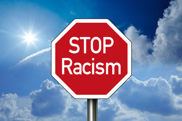 Road sign with STOP Racism with blue sky in the background