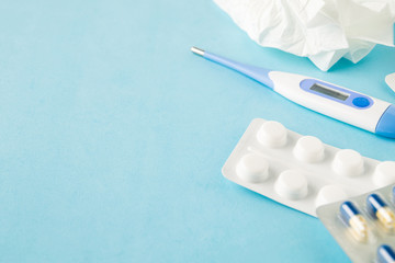 Selective focus on medical pills, used tissue and thermometer on blue background, copy space