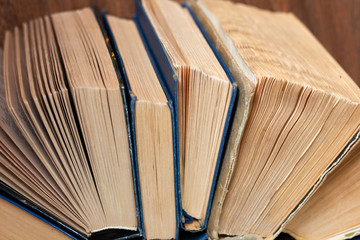 Old and well used hardback books or text books in a book shop or library. Many Books Piles. Hardback books on wooden table top view. Back to school background with copy space.