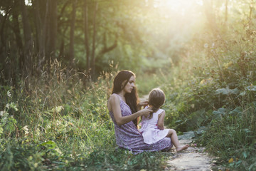 beautiful mother and daughter sitting on the grass in the Park