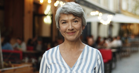 Portrait of beautiful senior Caucasian woman with grey hair looking straight at camera and smiling...