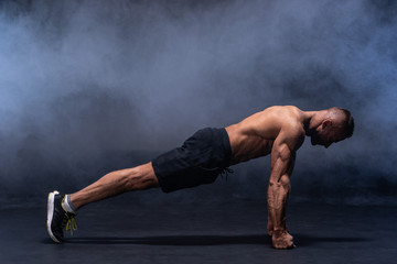 Muscular man doing calisthenic exercise isolated on the black background