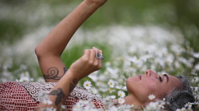Beautiful women laying on the flowers in the nature.