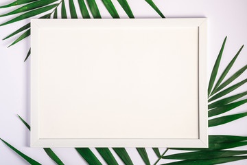 White picture frame with empty template on palm leaves, white background, mockup card