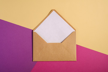 Kraft brown paper envelope with white empty card, pink, purple and cream yellow background, mockup blank letter