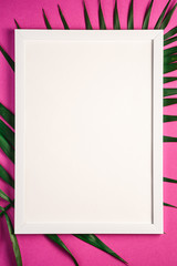 White picture frame with empty template on palm leaves, pink purple background, mockup card