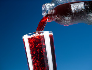 Pomegranate juice is pouring from a bottle into a glass