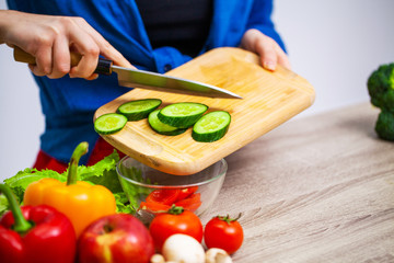 Concept of healthy eating, woman cuts fresh vegetables for salad