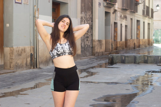 Portrait Of Relaxed Athlete, Caucasian Young Woman Touching His Head With Both Hands, Having Time For Rest, Looks Quiet And Peaceful, In The City, Short Black Tights. Place For Your Text In Copy Space