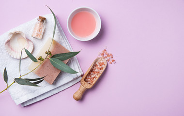 natural organic cosmetics with pink Himalayan salt, soap and eucalyptus branch on a pink background