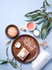 natural organic cosmetics with pink Himalayan salt, soap and eucalyptus branch on a blue background