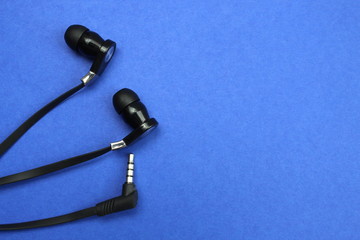 Black earphones for phone on a blue background