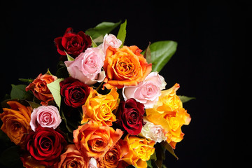 Bouquet of different color roses on a black background, closeup. Red, orange and pink flowers. Romantic Valentine's Day Gift