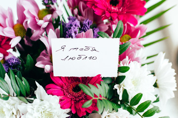 white card for a bouquet with the inscription I love you in Russian in a bright beautiful bouquet of flowers