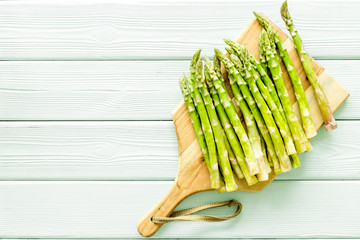 Cooking asparagus. Fresh steams on cutting board on green wooden background top-down copy space
