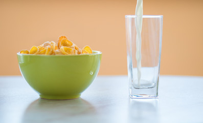cornflakes in the green dish, milk is flowing into the glass