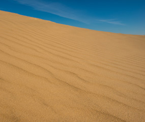 Fototapeta na wymiar Blue sky and sand surface in the dunes.